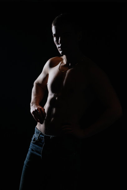 高对比剪影肖像的性感年轻男性模特赤膊摆姿势在一边。图片下载