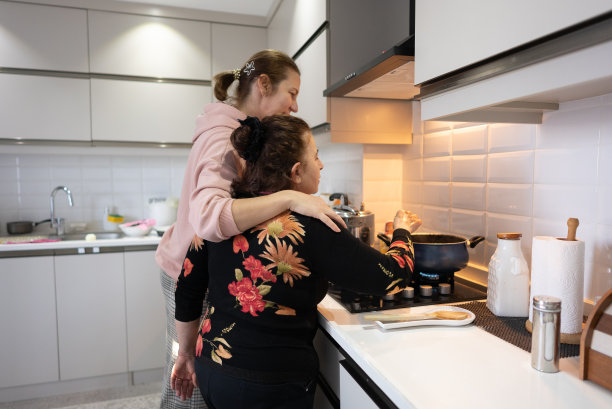 母亲和女儿在家庭厨房的炉子上亲密地做饭。图片下载