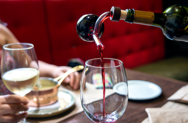 餐厅里有个不认识的人往杯子里倒酒图片下载