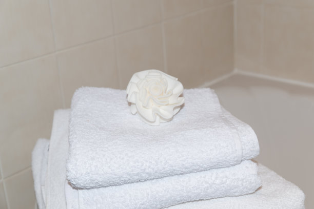 近距离观察一堆整齐堆叠的白色毛巾，上面放着白色的花海绵，图片下载