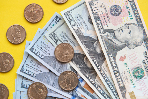 美元纸币和硬币。不同面额的美元纸币和硬币周围以黄色为背景图片下载