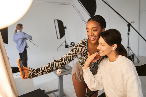 一名化妆师在拍摄后对着智能手机自拍，给她的多种族模特打了五针图片下载