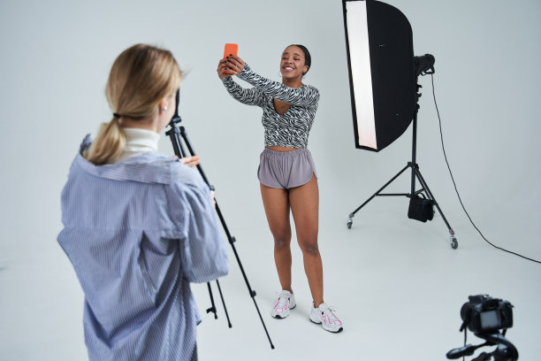 摄影师在拍摄期间休息，她的多种族模特正对着智能手机自拍图片下载