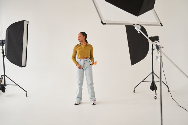 模特站在工作室的软盒子周围，手里拿着花等着拍照图片下载