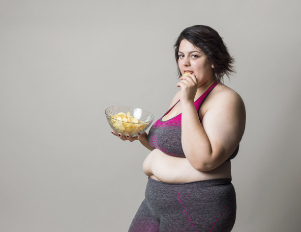 肥胖快乐的女人吃薯片的特写图片下载