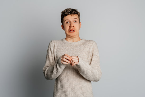 惊恐的少年惊恐地看着镜头，张大嘴巴，被商店里的高价震惊了，在灰色的背景下摆出姿势。人类反应的概念。图片下载