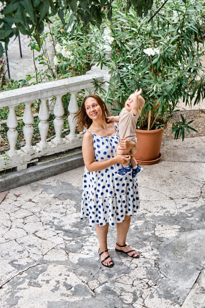 年轻的母亲抱着孩子站在公园的露台上图片下载