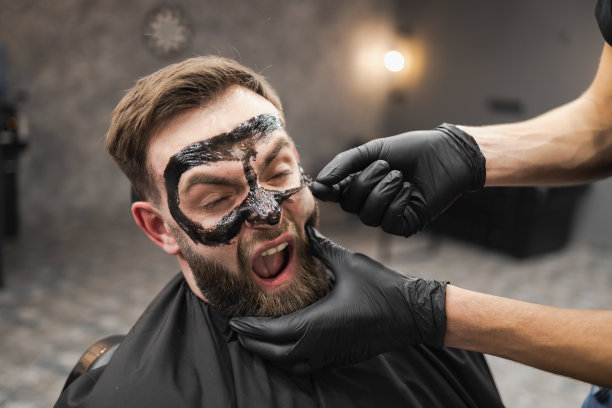 在美容院，一名惊恐的男子在取下黑色面膜时做了个鬼脸图片下载