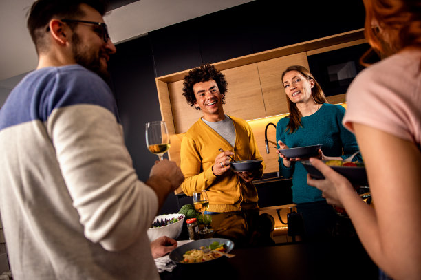 一群朋友在家里聚餐，喝着酒，吃着素食。图片下载