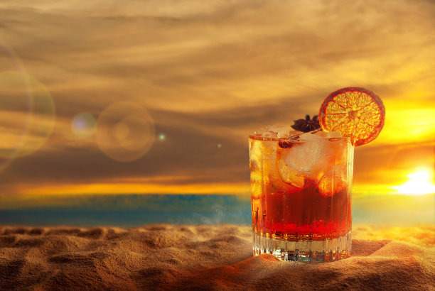 黄沙上的橙色鸡尾酒。酒精饮料加冰，橘子和肉桂。落日，大海和天空的背景。复制空间和玻璃附近的空闲空间。图片下载