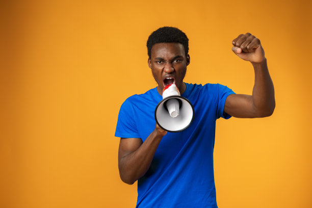 一个年轻的黑人在黄色背景下用扩音器大喊图片下载