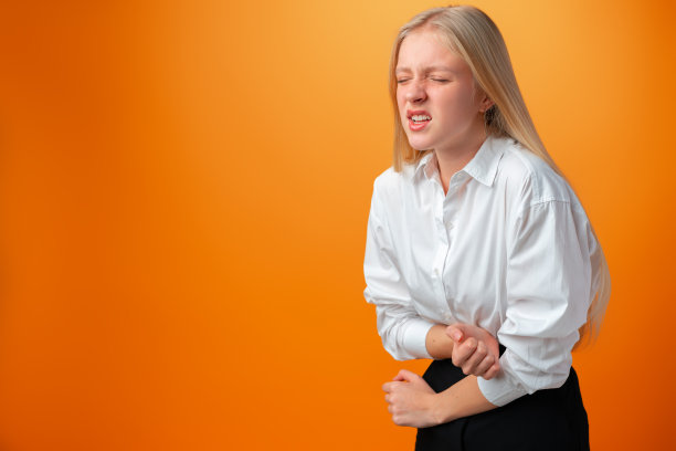 一个胃痛的十几岁女孩在工作室的橙色背景下图片下载
