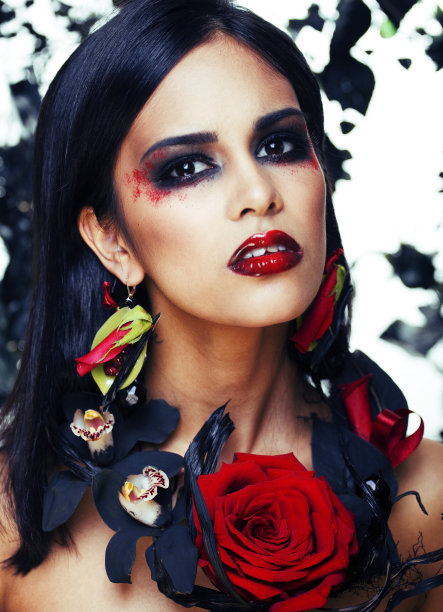 漂亮的黑发女人带着玫瑰首饰，黑色和红色，明亮的妆像吸血鬼特写的红唇图片下载