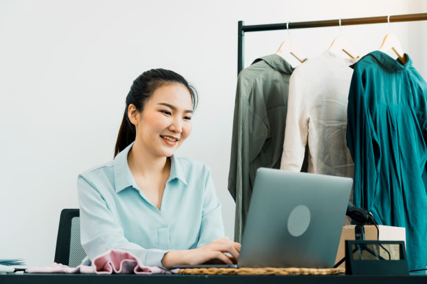 年轻的亚洲企业家在电脑前微笑着与顾客聊天。图片下载