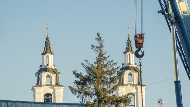 离焦的红色吊车钩在正十字教堂塔的背景上。建筑工地。图片下载