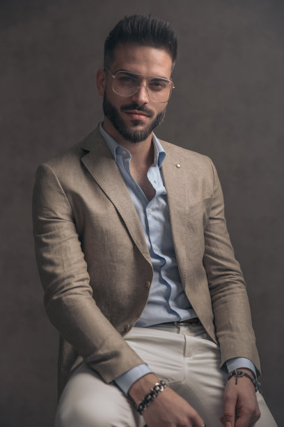 穿着米色西装，戴着眼镜的自信男子坐在那里图片下载