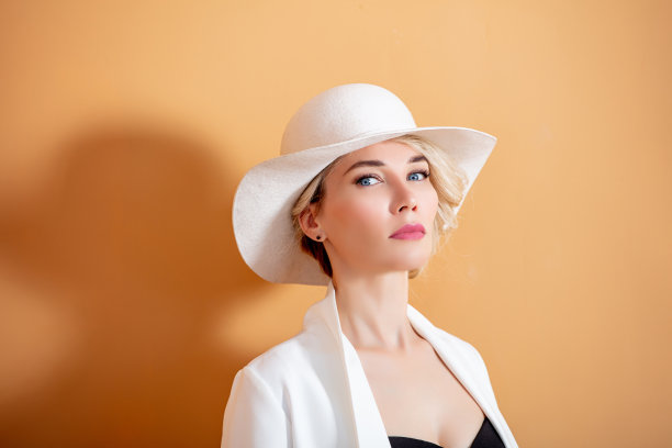 一个美丽的金发女人的肖像，蓝色的眼睛，白色的帽子和白色的夹克图片下载