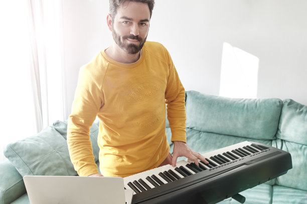 年轻人在家里玩数码钢琴很开心图片下载