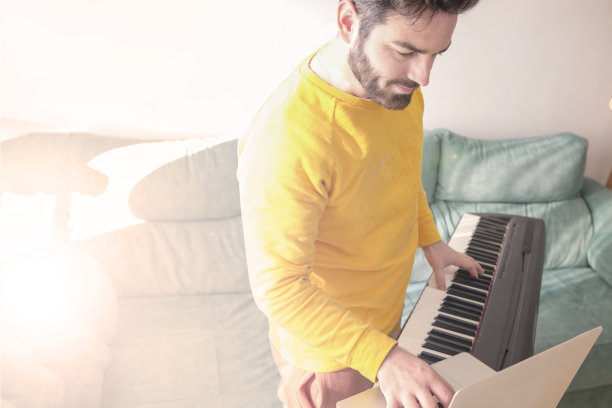 年轻人在家里玩数码钢琴很开心图片下载