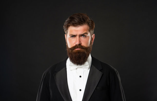 黑色背景下穿着燕尾服的大胡子男人，时尚达人图片下载