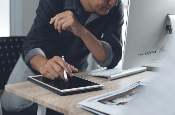 平面设计师，在现代办公室使用台式电脑和数码平板电脑工作图片下载
