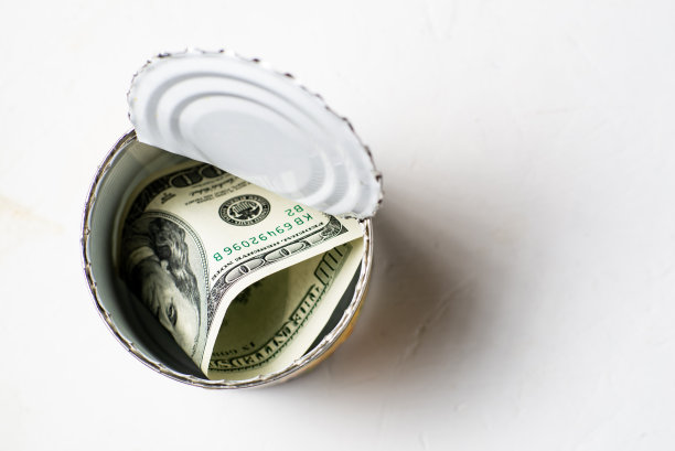 美元在一个开着的罐头里。保管现金，藏匿理念。是时候得到延期的，累积的钱了。白色背景。图片下载
