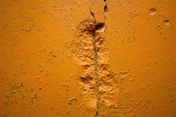 混凝土裂缝特写。摇摇欲坠的水泥墙。混凝土墙的破坏。橙色的墙上有裂缝。图片下载