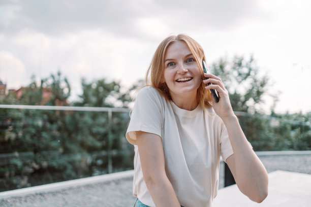 照片肖像的漂亮迷人的美丽的金发女人微笑着在户外电话交谈图片下载