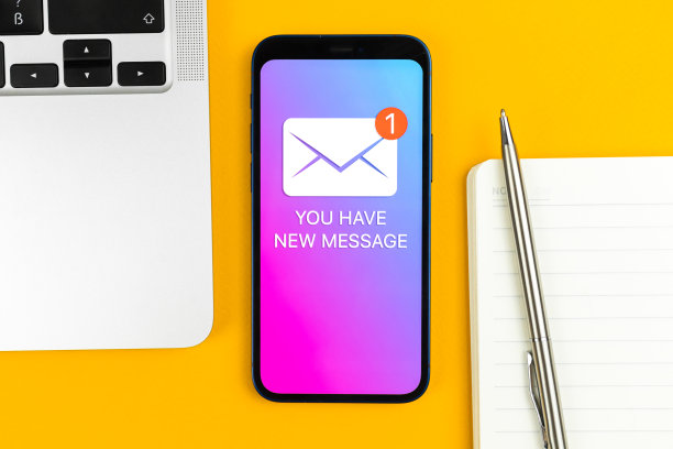 手机屏幕上的新消息图标。商务沟通，互联网和技术概念。办公桌与笔记本电脑顶视图背景照片图片下载