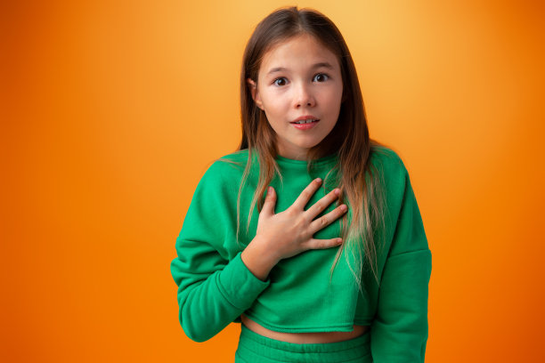 震惊的快乐少女在橙色背景前图片下载