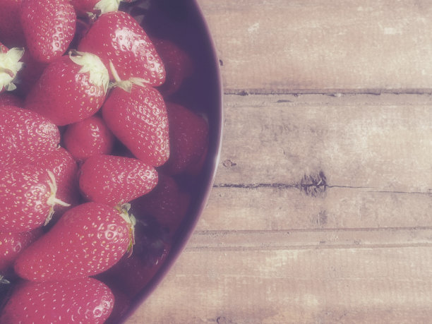 草莓盘，木制背景。深色陶瓷盘子和美味的红色大草莓园。健康的食物，维他命和素食。有食物的静物。副本的空间。平的。图片下载