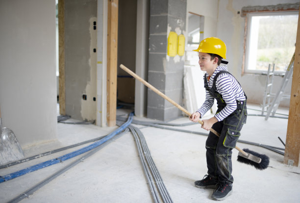 戴着黄色头盔的酷小子拿着扫帚在工地上图片下载