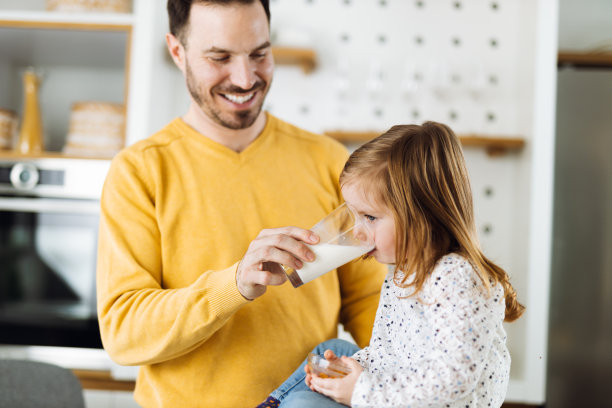 小女孩和她的父亲在厨房里喝牛奶图片下载