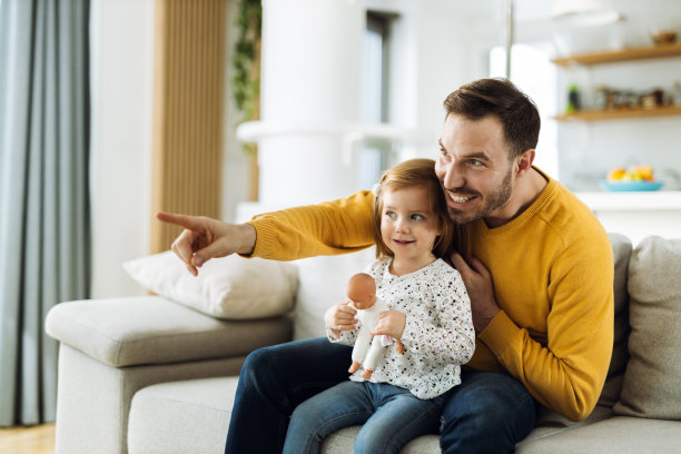 快乐的爸爸和他的小女儿在客厅的沙发上看电视图片下载