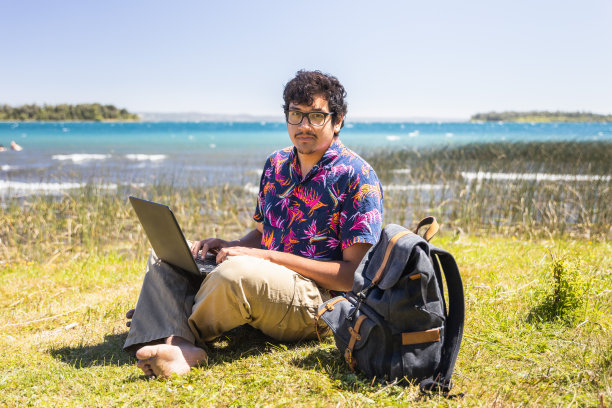 一个拉丁青年在湖边做远程在线工作。远程工作的概念。数字生活图片下载