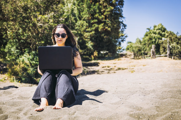 年轻女子在沙滩上做远程在线工作。远程工作的概念。数字生活图片下载