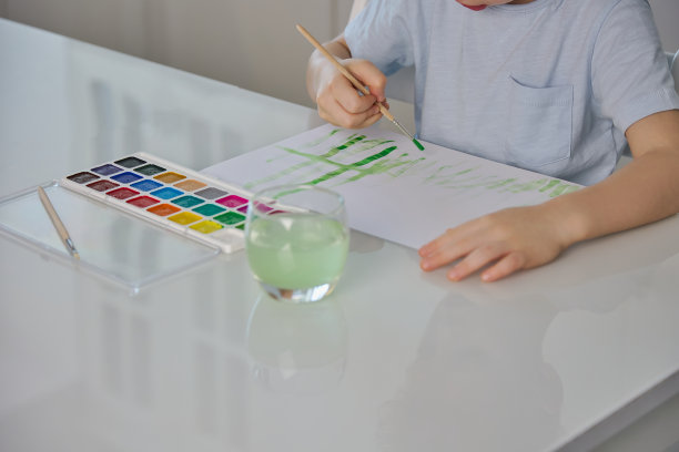 一个无名的小孩用画笔在纸上画画图片下载