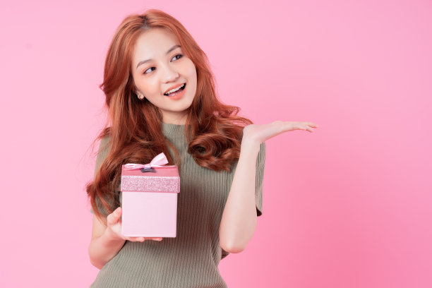 年轻的亚洲妇女拿着粉红色背景的礼品盒图片下载