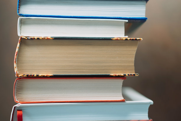 不同颜色和大小的书尾被堆放在一个模糊的背景上图片下载
