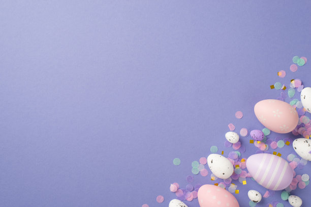 在孤立的紫色背景copyspace上，几个不同大小的彩色复活节彩蛋和粉红色、紫色、金色和蓝色的粉彩纸屑的俯视图图片下载