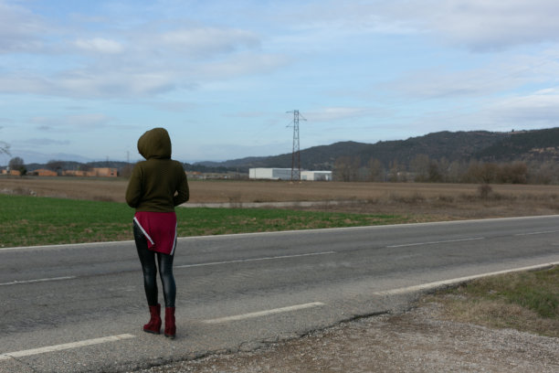 戴头巾的女人，手插在口袋里，在路上等待。认不出来图片下载