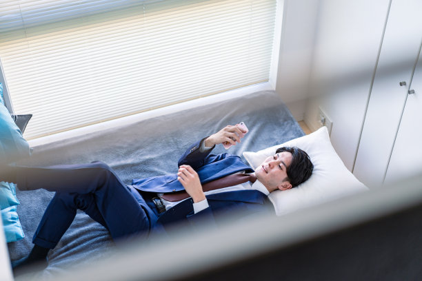 一位商人在床上使用智能手机图片下载