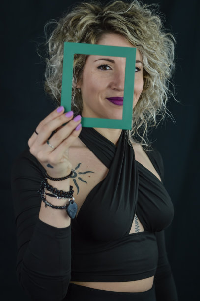 相框美人-一个美丽的卷发金发女人的肖像，在她的脸前拿着一个小的相框-独特和多样性的概念图片下载
