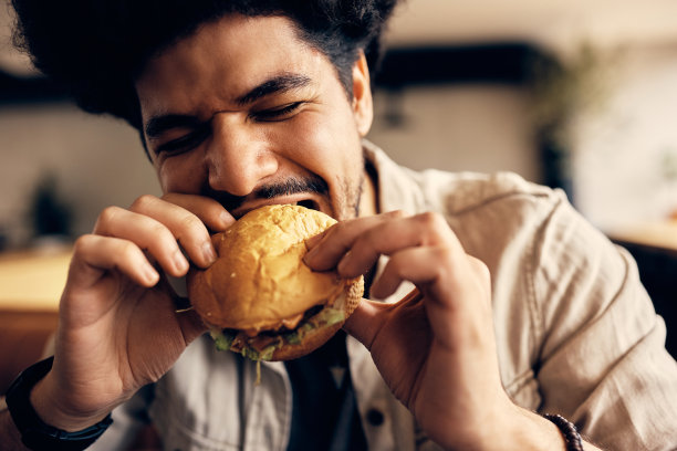 年轻的穆斯林男子在酒吧吃芝士汉堡。图片下载