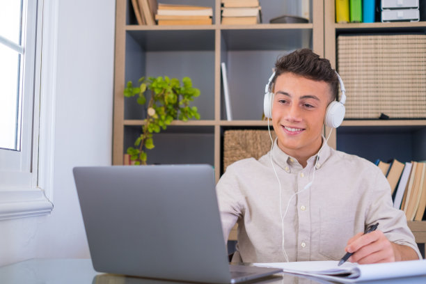 快乐轻松的千禧一代青少年商人，戴上无线耳机，看向别处，在工作场所休息，完成工作，听音乐，听播客，感觉心平气和的概念，坐在桌前，在阳光明媚的办公室写作图片下载