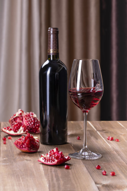 一杯红石榴酒和石榴放在木制的背景上图片下载