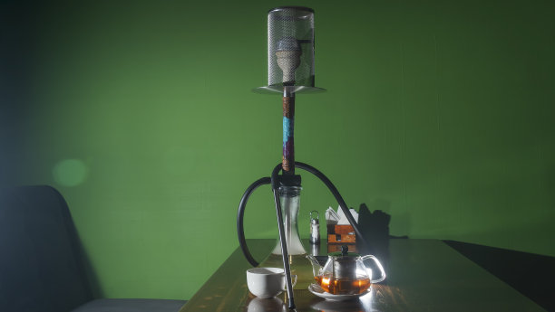 传统的阿拉伯水烟和带镜头光晕的茶。一壶茶和正在吸烟的水烟在深绿色的背景。图片下载