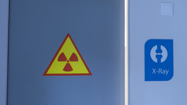 在上锁的门和墙上张贴x光警告标志。门上黄色的放射性标志。x射线内阁。图片下载