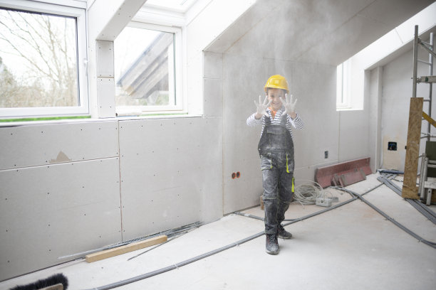 酷酷的小男孩戴着黄色安全帽，在建筑工地摆造型，玩得很开心图片下载