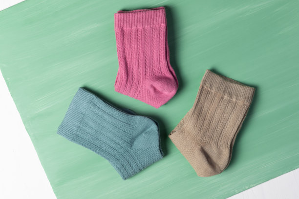 多色袜子在绿色的背景。前视图。在寒冷的季节有许多不同的袜子。袜子散落在明亮的背景上。袜子形状的衣服。图片下载